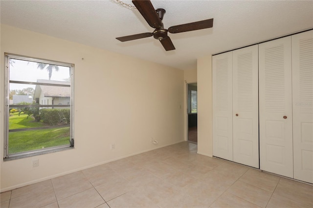 unfurnished bedroom with a closet, baseboards, a textured ceiling, and light tile patterned flooring