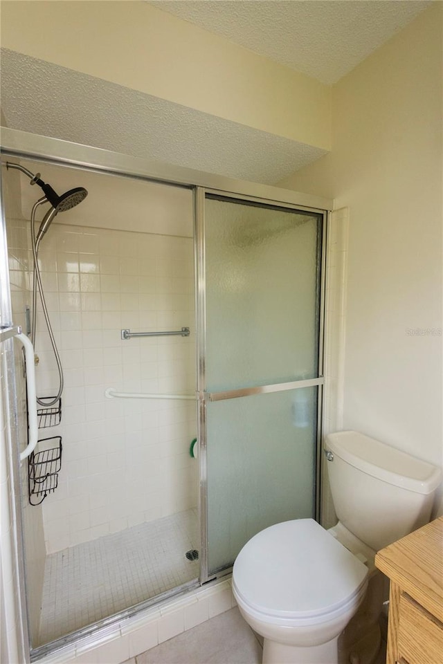 full bathroom featuring toilet, a stall shower, and a textured ceiling