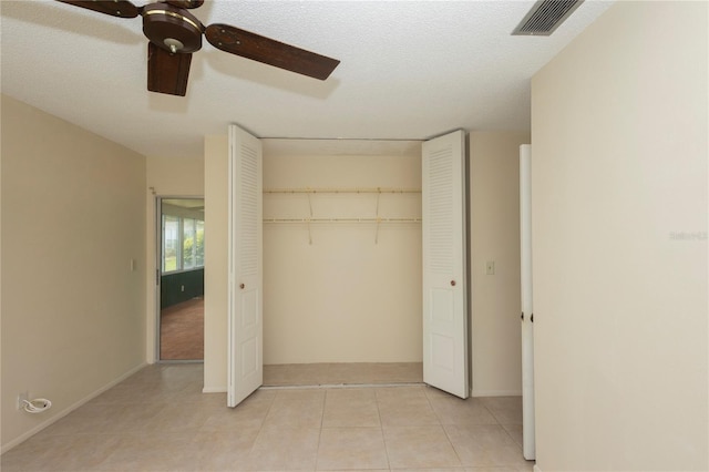 unfurnished bedroom with visible vents, ceiling fan, light tile patterned flooring, a closet, and a textured ceiling