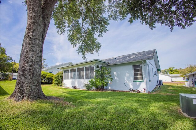 back of house featuring stucco siding, a lawn, and a sunroom