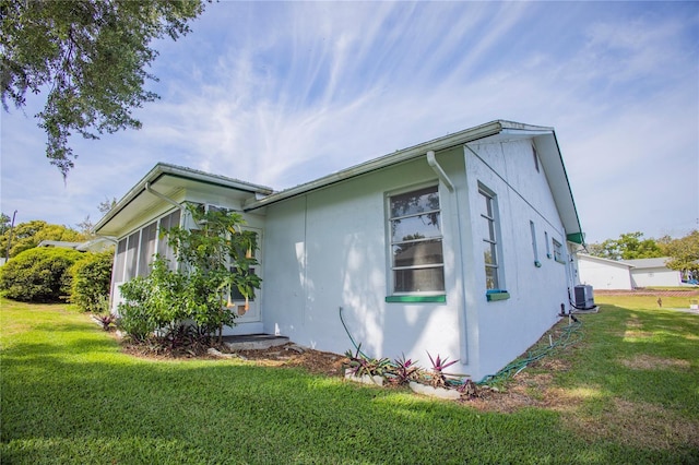 view of property exterior with a yard, central AC unit, and stucco siding