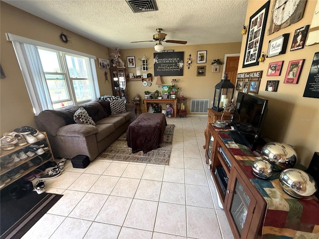 living area with light tile patterned floors, a ceiling fan, visible vents, and a textured ceiling