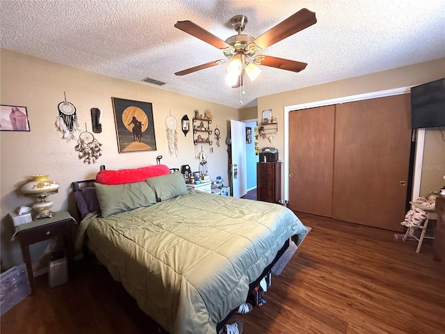 bedroom with visible vents, ceiling fan, wood finished floors, a closet, and a textured ceiling