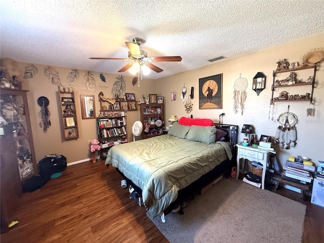 bedroom with visible vents, a textured ceiling, wood finished floors, and a ceiling fan