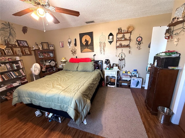 bedroom featuring ceiling fan, visible vents, a textured ceiling, and wood finished floors