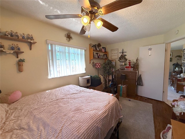 bedroom featuring wood finished floors, a textured ceiling, and ceiling fan