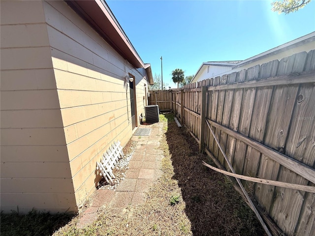 view of property exterior featuring concrete block siding, fence, and central AC