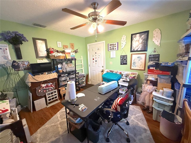 home office with visible vents, wood finished floors, a textured ceiling, and ceiling fan