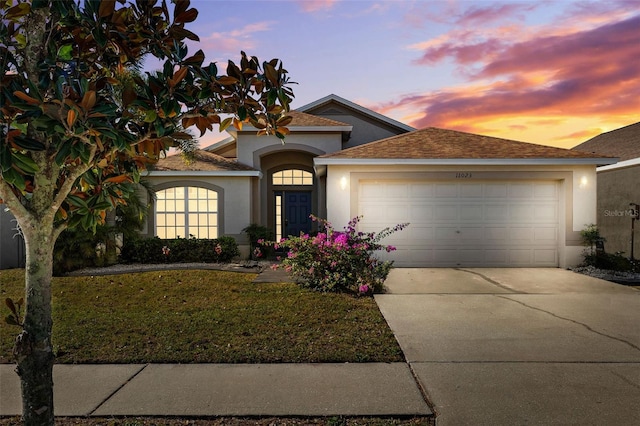 view of front of house with a front lawn, stucco siding, a garage, and concrete driveway