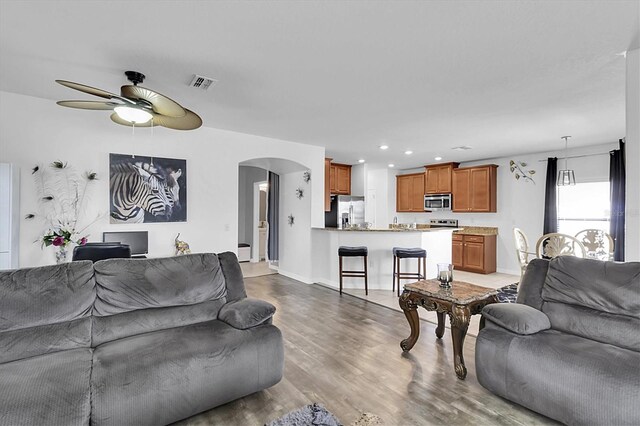 11895 Crestridge Loop, New Port Richey, FL 34655 - living room with baseboards, arched walkways, visible vents, ceiling fan, and wood finished floors