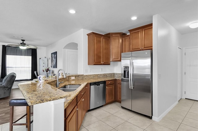 11895 Crestridge Loop, New Port Richey, FL 34655 - kitchen featuring a peninsula, light stone countertops, a ceiling fan, appliances with stainless steel finishes, and a sink