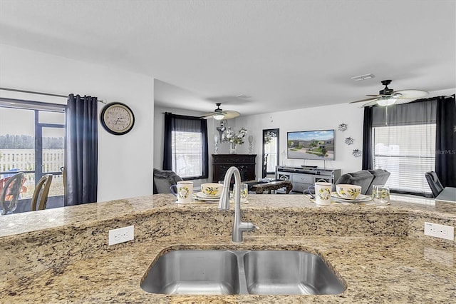 11895 Crestridge Loop, New Port Richey, FL 34655 - kitchen with open floor plan, a sink, visible vents, light stone countertops, and ceiling fan