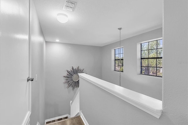 11895 Crestridge Loop, New Port Richey, FL 34655 - hall with baseboards, visible vents, an upstairs landing, and wood finished floors