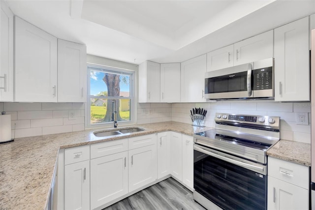 8626 White Springs Dr, New Port Richey, FL 34655 - kitchen with backsplash, white cabinets, appliances with stainless steel finishes, and a raised ceiling