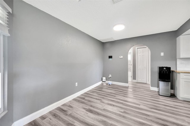 8626 White Springs Dr, New Port Richey, FL 34655 - interior space with arched walkways, baseboards, light wood finished floors, and a textured ceiling