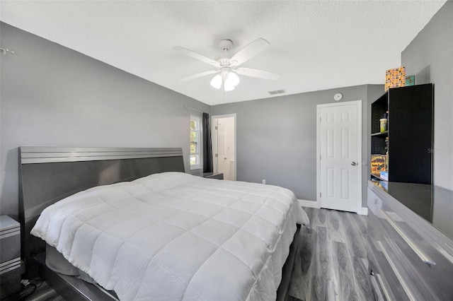 8626 White Springs Dr, New Port Richey, FL 34655 - bedroom with baseboards, a textured ceiling, visible vents, a ceiling fan, and wood finished floors