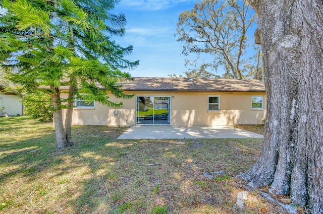8626 White Springs Dr, New Port Richey, FL 34655 - back of property featuring stucco siding, a lawn, and a patio