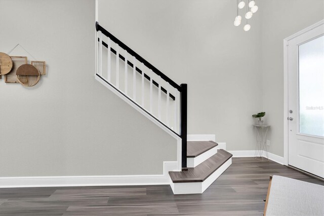 foyer entrance with wood finished floors, baseboards, and stairway