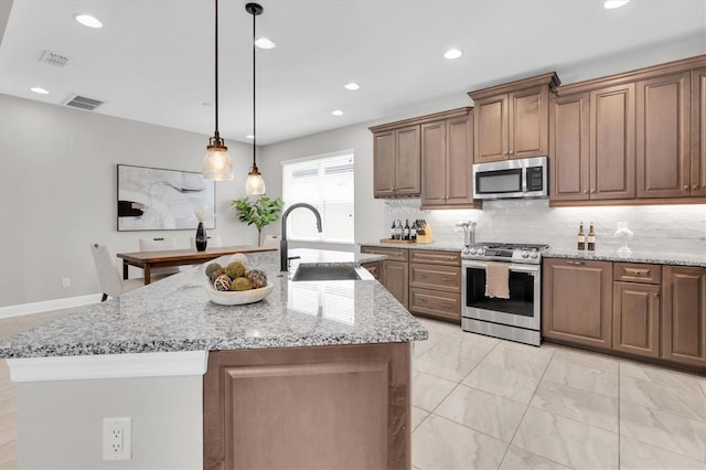 kitchen with backsplash, visible vents, stainless steel appliances, and a sink