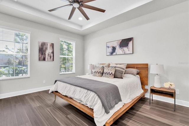 bedroom with wood finished floors, ceiling fan, a raised ceiling, baseboards, and recessed lighting