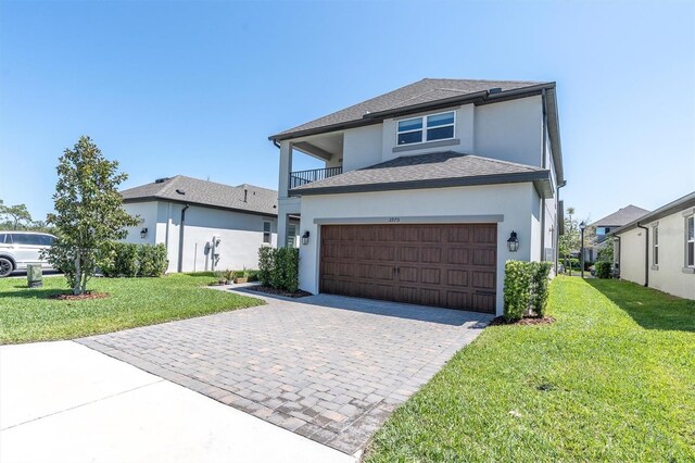 view of front of home featuring an attached garage, a front yard, stucco siding, and decorative driveway