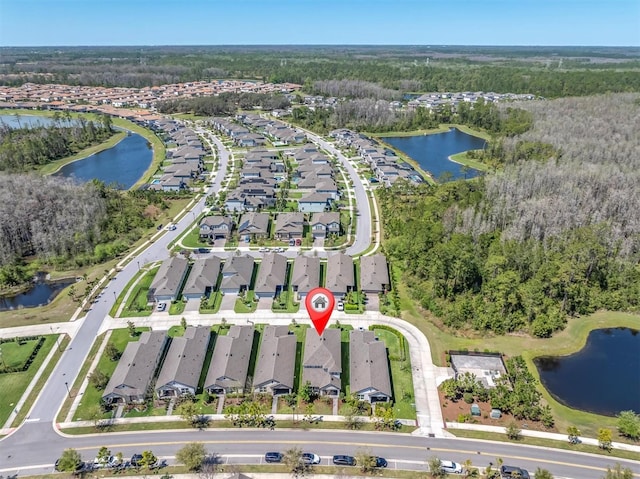 drone / aerial view featuring a water view, a residential view, and a wooded view