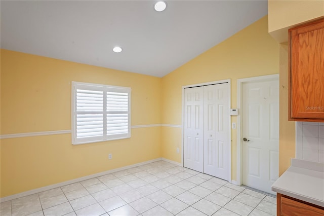 303 Rochester St, Spring Hill, FL 34609 - kitchen featuring lofted ceiling, brown cabinetry, light countertops, light tile patterned floors, and baseboards