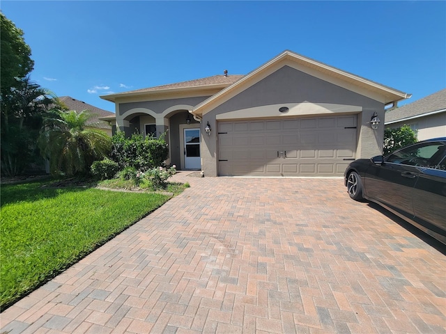 view of front of property with a garage, a front yard, stucco siding, and decorative driveway