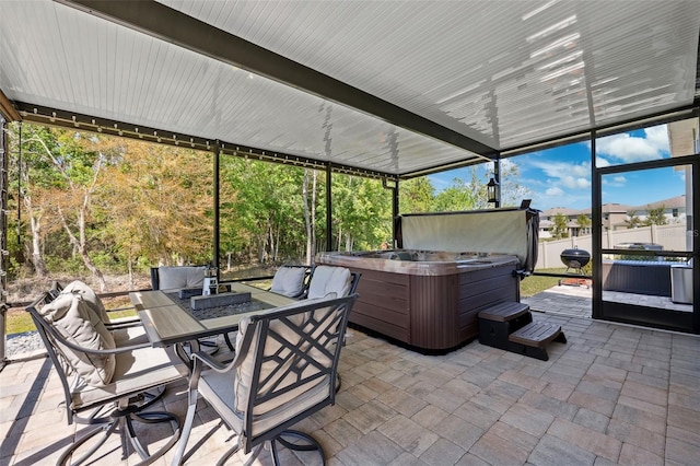 view of patio / terrace with glass enclosure, outdoor dining space, and a hot tub