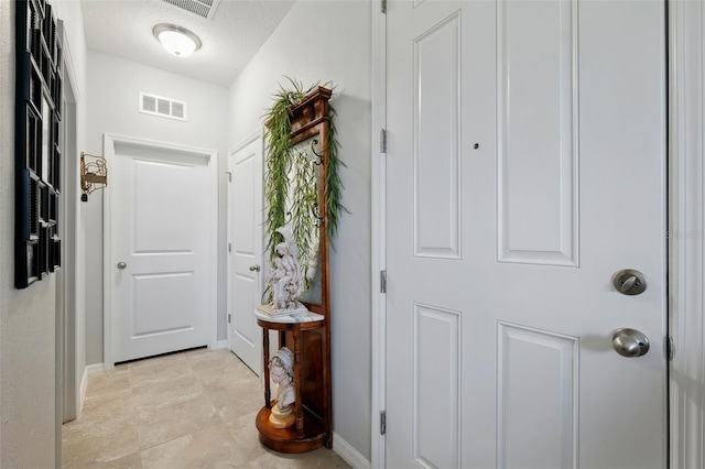 foyer with baseboards, visible vents, and a textured ceiling