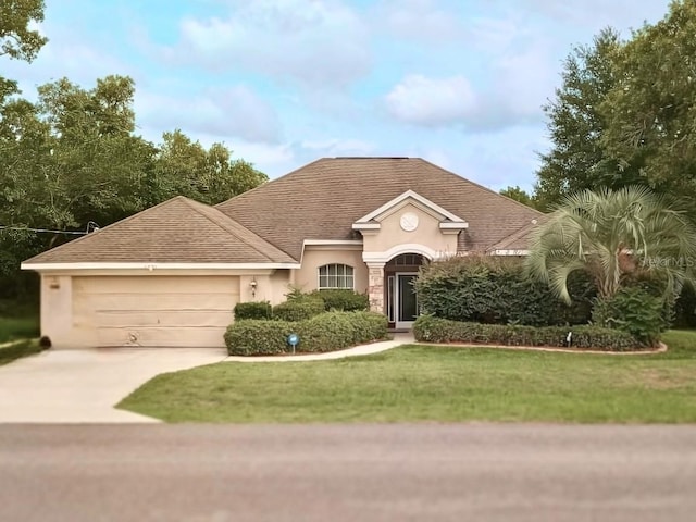 view of front of home with stucco siding, an attached garage, driveway, a front lawn, and a shingled roof