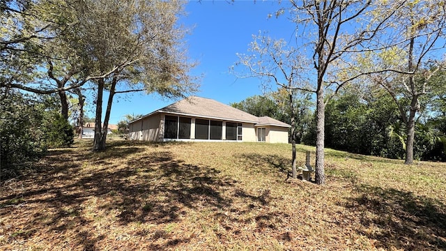 back of property with a sunroom and a lawn