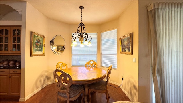 dining space featuring a notable chandelier, dark wood-type flooring, and baseboards