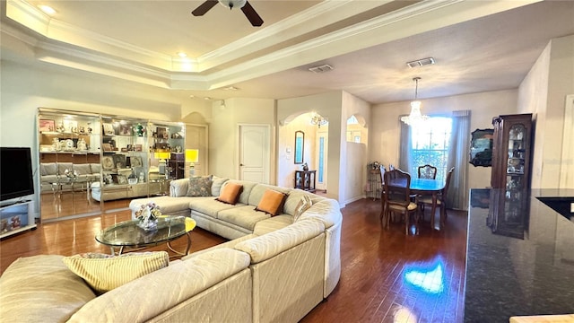 living area with crown molding, wood finished floors, ceiling fan with notable chandelier, visible vents, and arched walkways