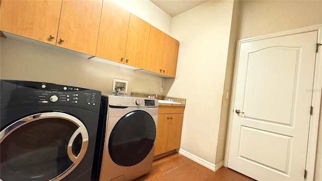 laundry room with washer and clothes dryer, a sink, light wood-style flooring, baseboards, and cabinet space