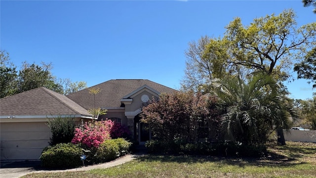 view of property hidden behind natural elements with roof with shingles and an attached garage