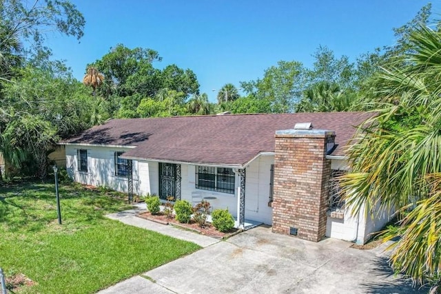 single story home featuring a front yard, a chimney, a shingled roof, concrete driveway, and a garage