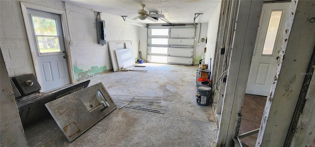 garage featuring electric panel, concrete block wall, and ceiling fan
