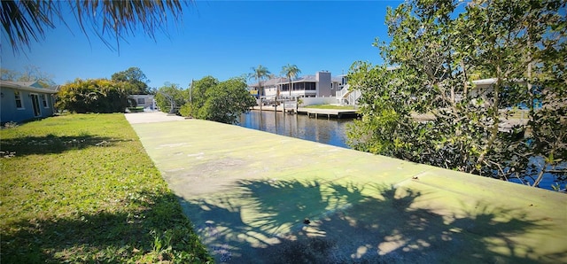 view of dock with a yard and a water view