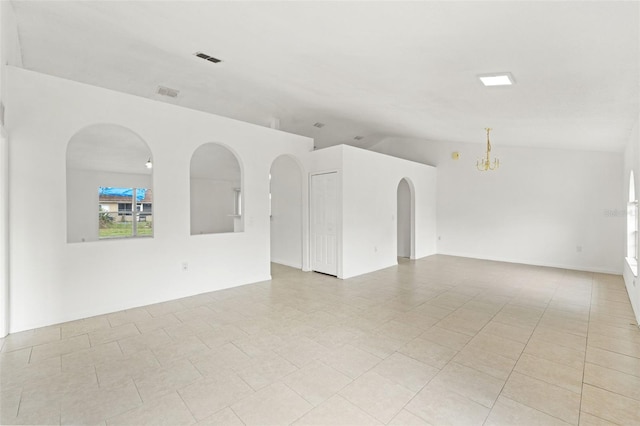 empty room featuring a chandelier, arched walkways, and lofted ceiling