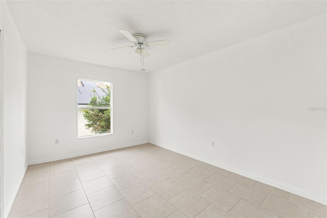 spare room with a ceiling fan, a textured ceiling, light tile patterned flooring, and baseboards