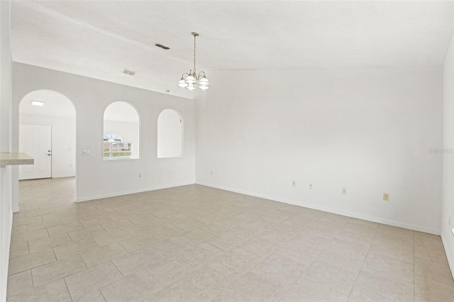 empty room with a chandelier, arched walkways, and baseboards