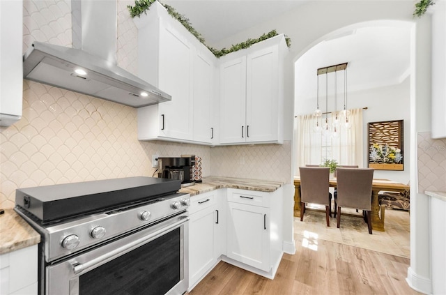10623 Marsha Dr, New Port Richey, FL 34655 - kitchen with wall chimney exhaust hood, electric stove, arched walkways, light wood-style flooring, and white cabinets
