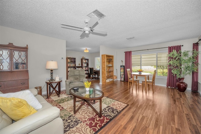 living area with baseboards, a textured ceiling, ceiling fan, and wood finished floors