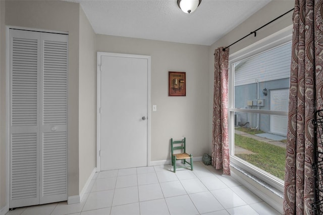 unfurnished dining area featuring a textured ceiling, baseboards, and tile patterned flooring