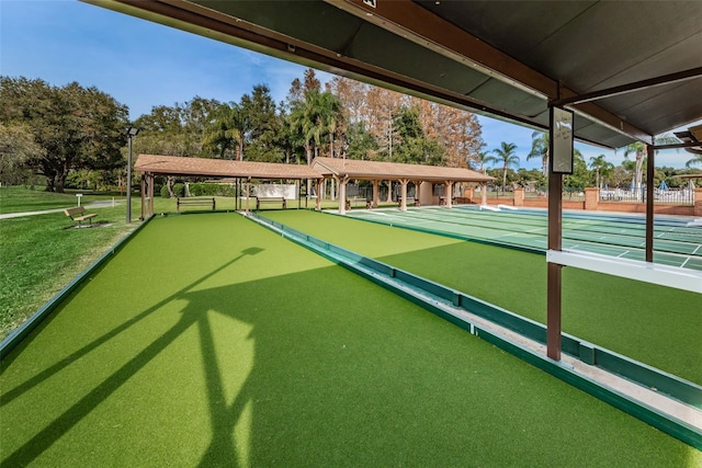 view of community with a yard and shuffleboard