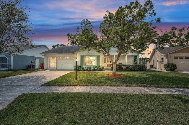 ranch-style home featuring concrete driveway, an attached garage, and a front lawn