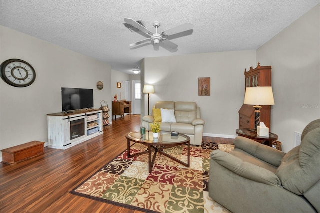 living room featuring a textured ceiling, baseboards, a ceiling fan, and wood finished floors