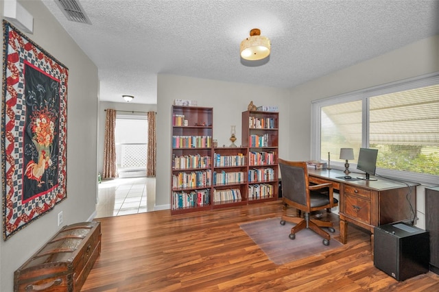 home office with visible vents, a textured ceiling, and wood finished floors