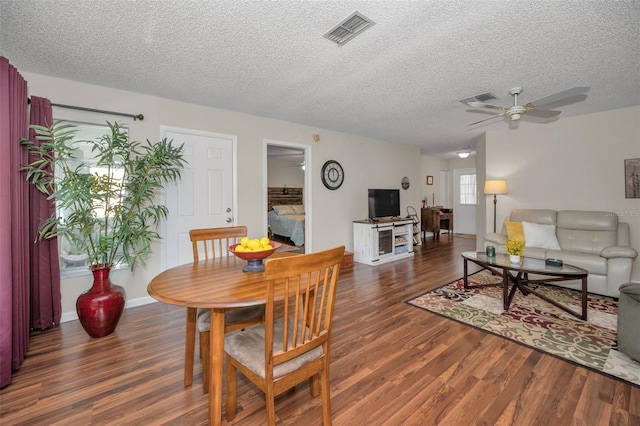 dining space with visible vents, a ceiling fan, a textured ceiling, and wood finished floors